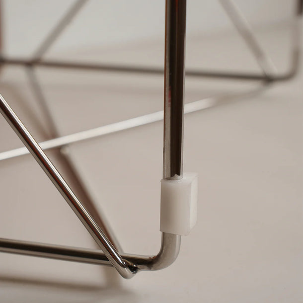 Close-up of a metal chair arm with a white cushion on a neutral background