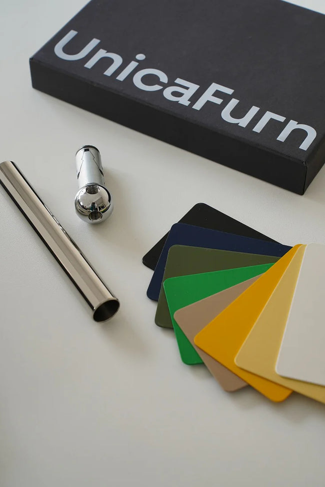 UnicaFurn color swatch book with metallic rod and small metal object on a light surface