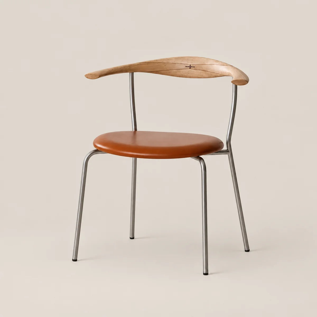 A mid-century modern dining chair featuring a curved natural wood backrest, a round cognac brown leather seat, and a slim silver metal frame, set against a solid warm beige background.