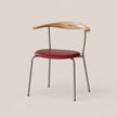 A modern dining chair featuring a curved natural wood backrest, a deep red upholstered seat cushion, and a slim silver metal frame, set against a solid light beige background.