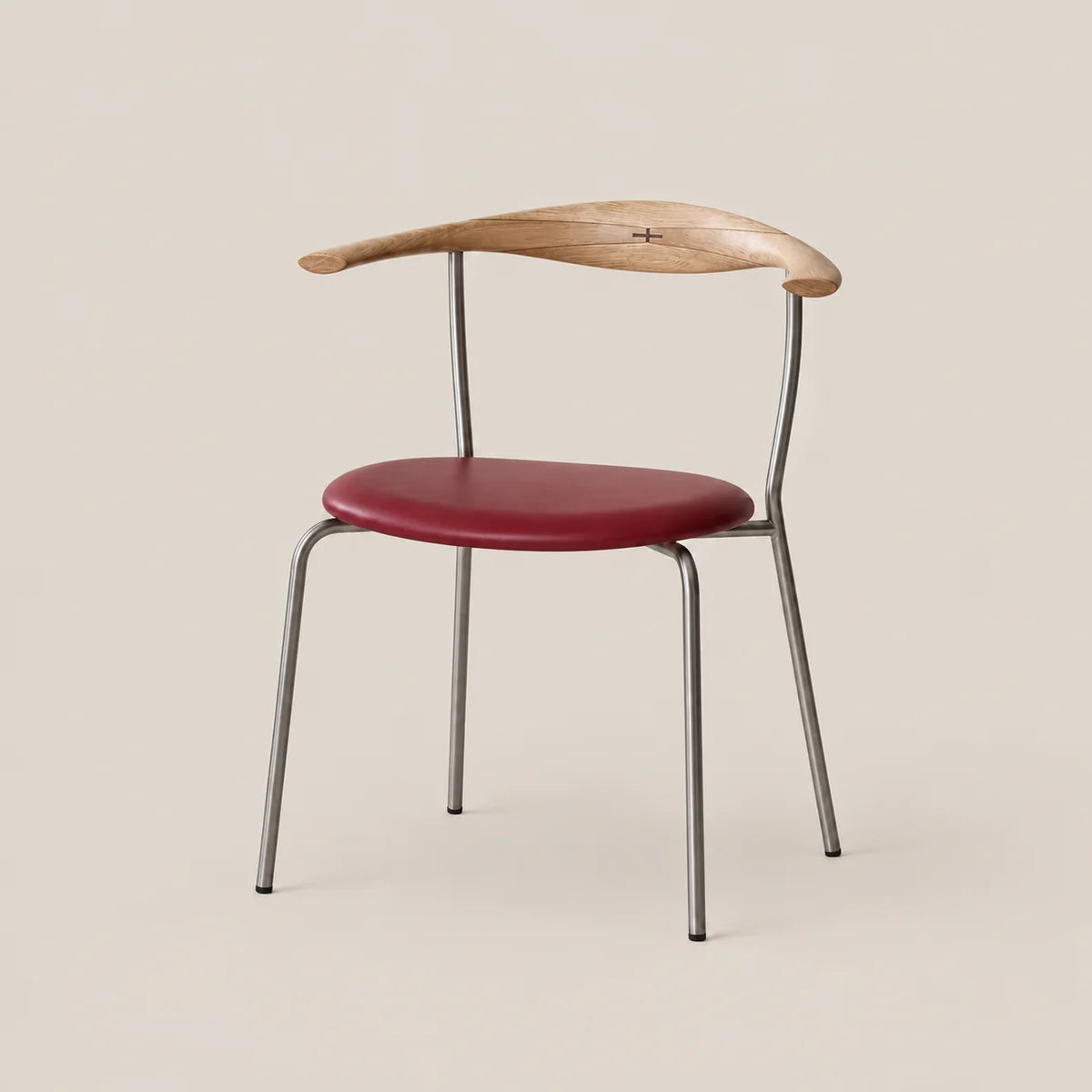 A modern dining chair featuring a curved natural wood backrest, a deep red upholstered seat cushion, and a slim silver metal frame, set against a solid light beige background.