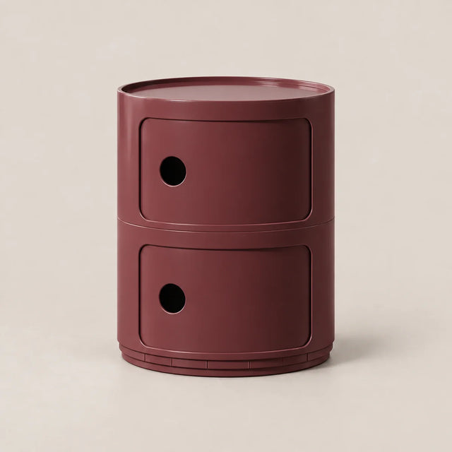 A modern two-tier cylindrical side table or storage unit in a matte burgundy finish, set against a clean, warm off-white background.