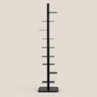 A black metal display stand with a single vertical pole, eight horizontal shelves, and a square base, shown against a solid light beige background.