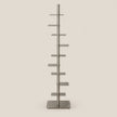 A tall, slim metal display stand with multiple horizontal shelves on a vertical pole, shown against a plain light beige background.