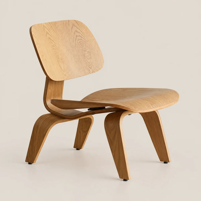 A mid-century modern wooden lounge chair with a curved plywood shell and tapered legs, shown on a solid light beige background.