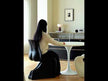 A sculptural black chair with a continuous, organic, undulating form that seamlessly blends the seat and backrest, featuring a matte, molded finish.