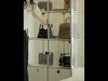 A modular furniture display cabinet featuring a glass section crafted from clear tempered glass and a base composed of solid panels. Housing a collection of luxury handbags, the cabinet exudes a distinct sense of 