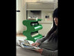 A glossy green, wavy sculptural PC side table with built-in storage shelves.
