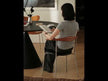 A modern dining chair with a curved wooden backrest, a black seat, and slender stainless steel legs.