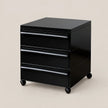A black three-drawer rolling storage cabinet with a glossy finish and casters, shown on a solid beige background.