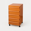 An orange rolling file cabinet with six drawers and black caster wheels, photographed on a clean white background.