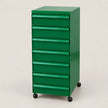 A green 7-drawer rolling file cabinet with black caster wheels, photographed on a clean, light beige studio background.
