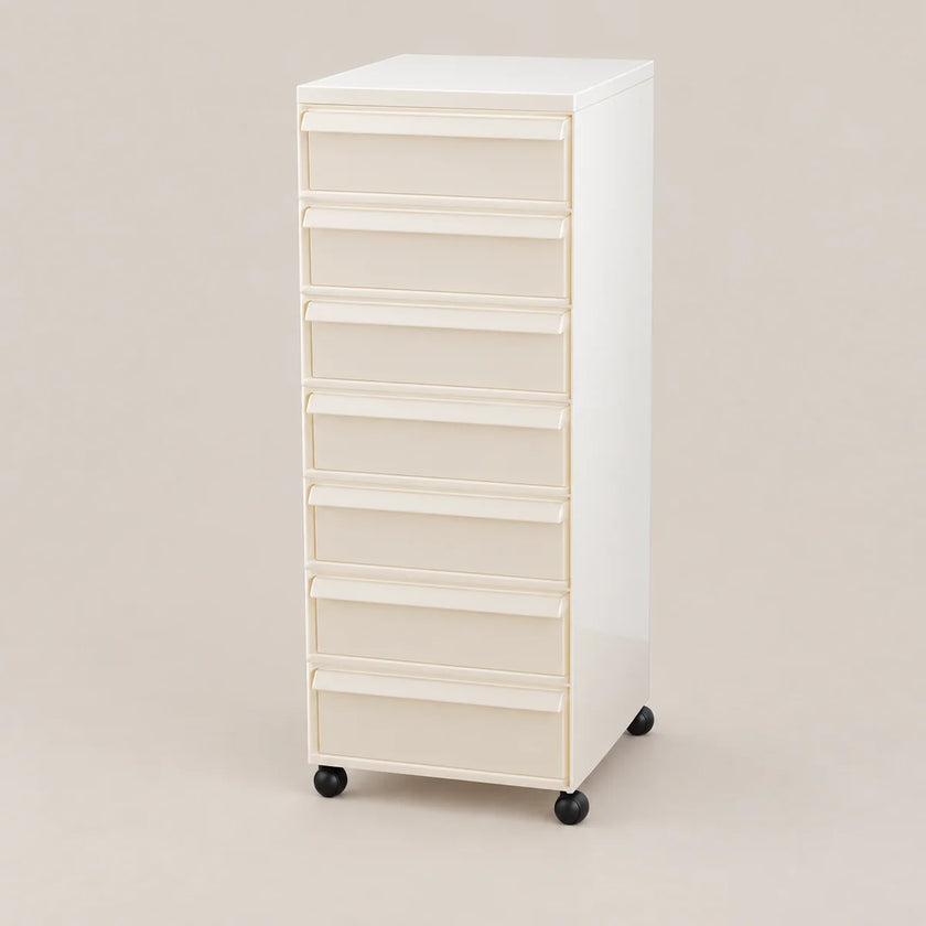 A tall, narrow white rolling storage cabinet with eight drawers and black caster wheels, photographed against a plain warm beige studio background.