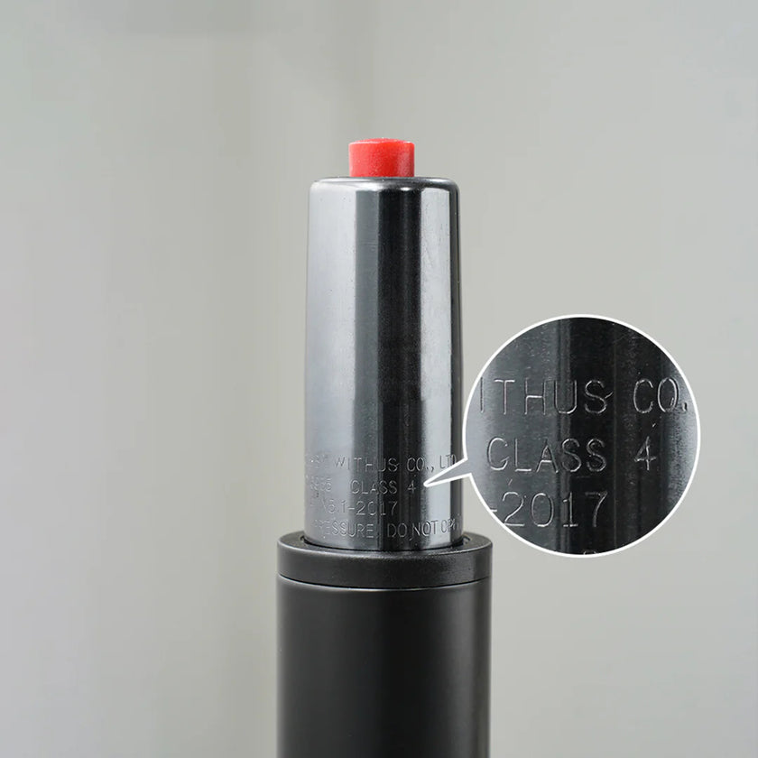 Close-up of a cylindrical object with a red cap and engraved text on a gray background