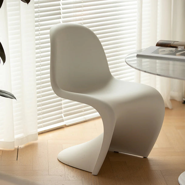 White chair in a room with a glass table and curtains