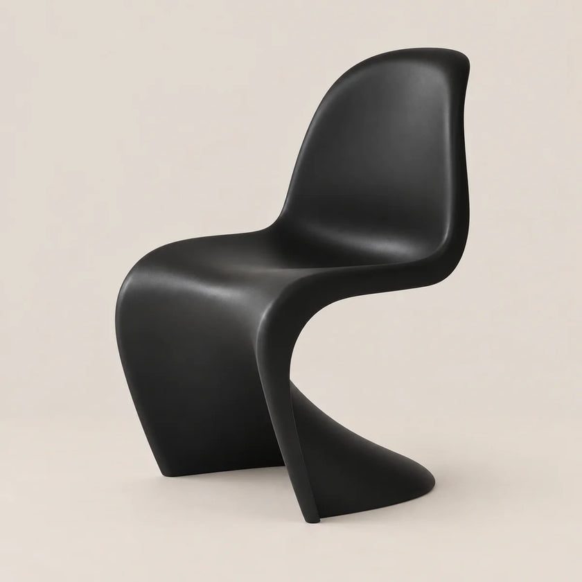 A modern sculptural black chair with a curved shell seat and integrated base, photographed against a plain warm beige studio background.