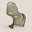 A modern translucent smoked gray plastic chair with a curved ergonomic design, shown against a solid light beige background.