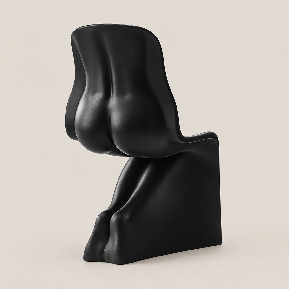 A modern sculptural black chair with an abstract, organic form, photographed against a solid, warm off-white background.