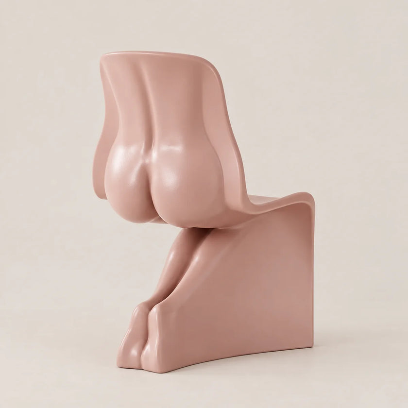 A sculptural, abstract side chair in a matte dusty rose pink color, photographed against a solid, warm off-white background.