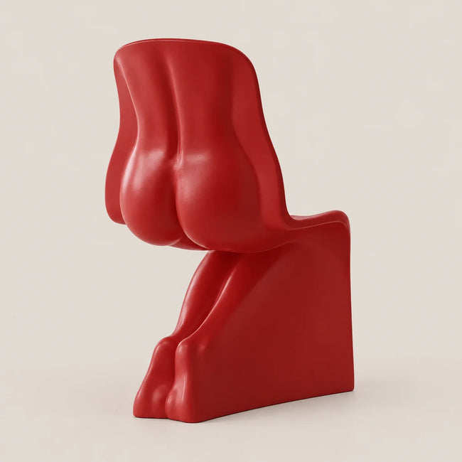 A bold, sculptural red chair with an abstract, organic shape, photographed against a solid, warm off-white background.