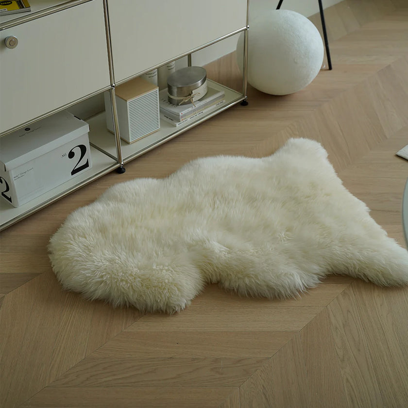 White fur rug on a wooden floor with a shelf in the background
