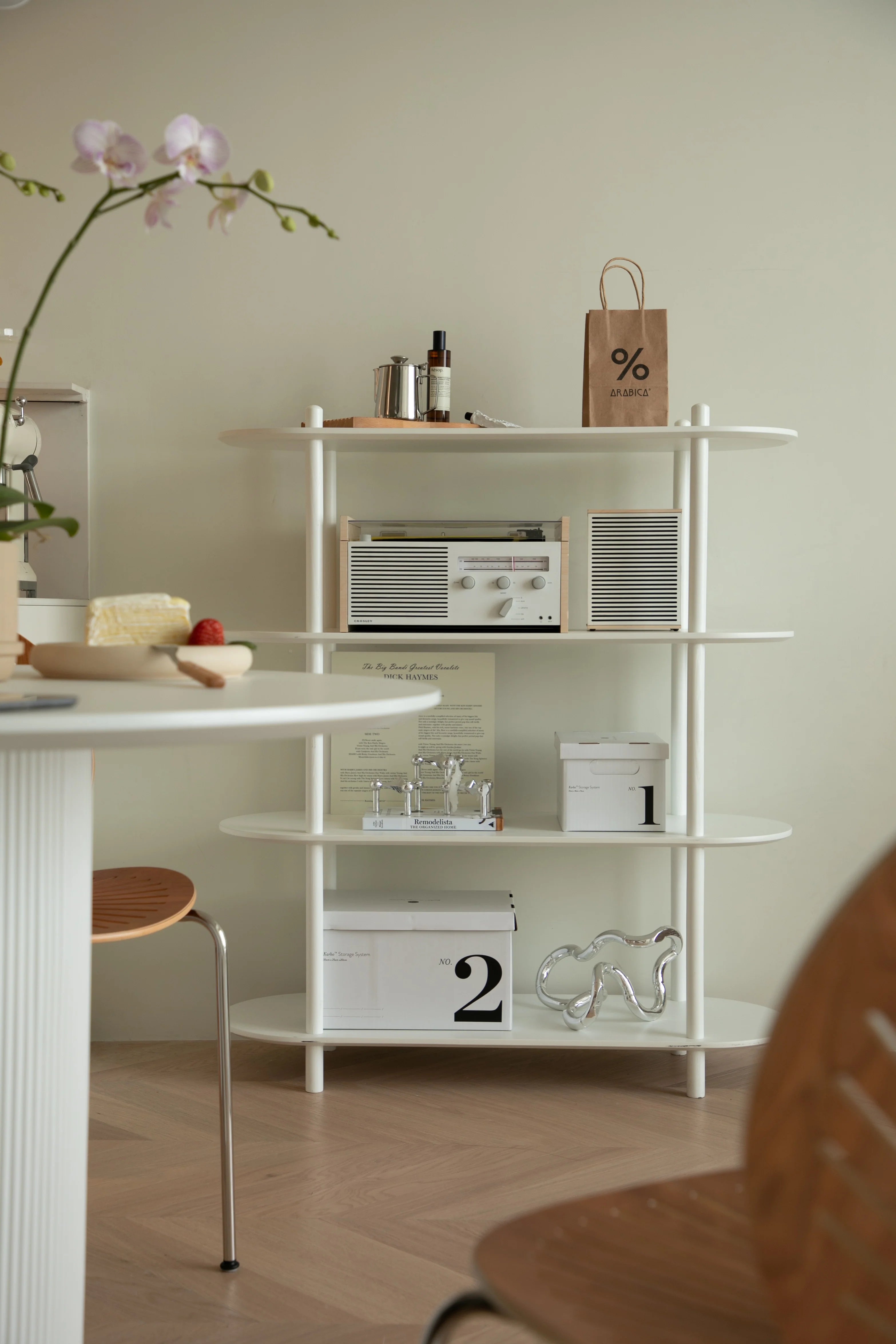 White shelving unit with decorative items against a light green wall