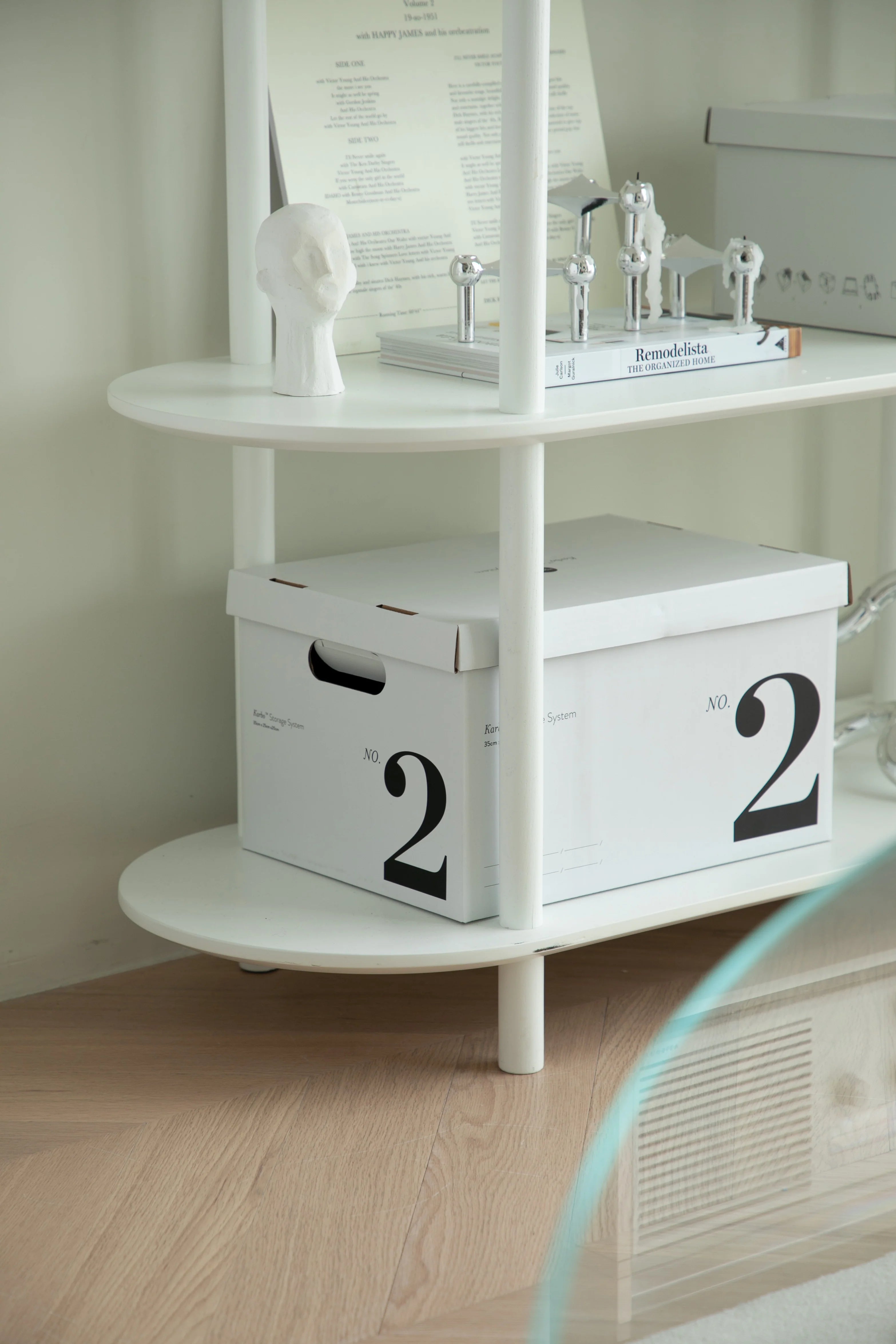 White storage boxes with the number '2' on a shelf against a light wall.