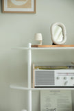 White shelf with a vintage radio, lamp, and abstract sculpture against a light green wall.