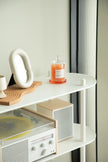 White shelf with vinyl record player, candle, and decorative items against a light wall.
