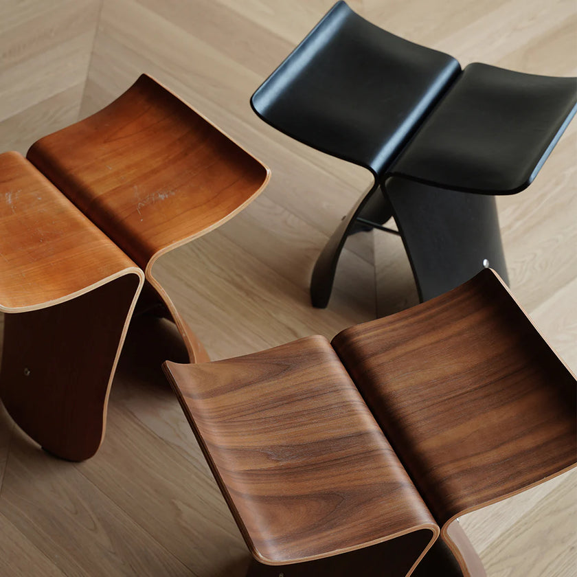 Three wooden stools with different finishes on a light wood floor.