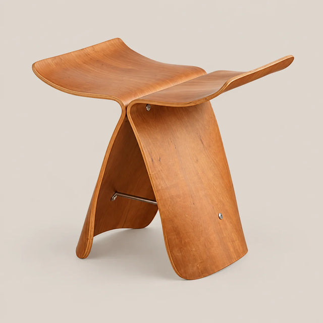 A mid-century modern wooden stool with a sculptural, curved plywood shell design, shown on a solid light beige background.