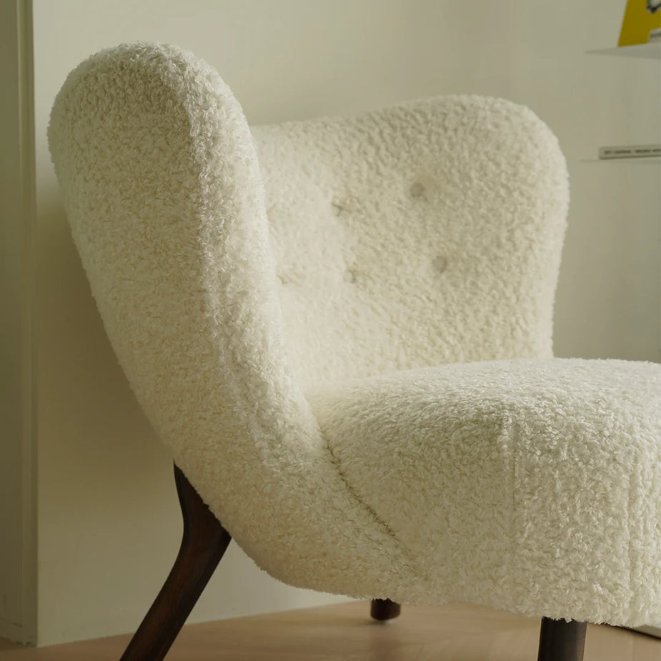 White textured chair with wooden legs against a neutral wall
