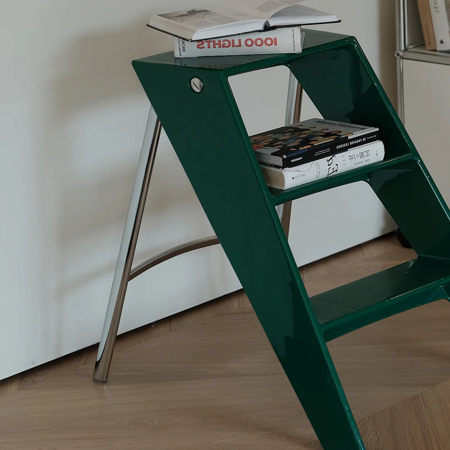 Green step ladder with books on a white wall background