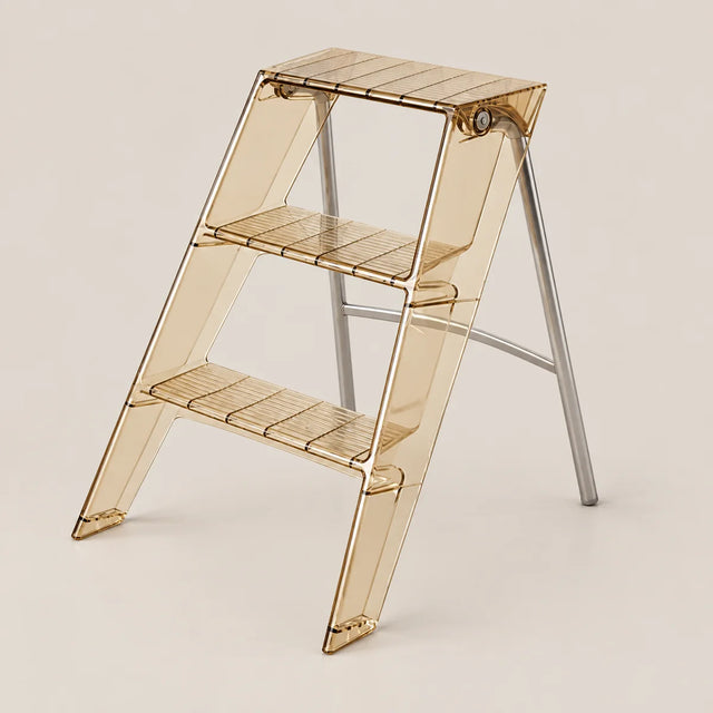 A three-step folding step ladder made of translucent amber-tinted plastic with silver metal support legs, shown on a plain beige studio background.