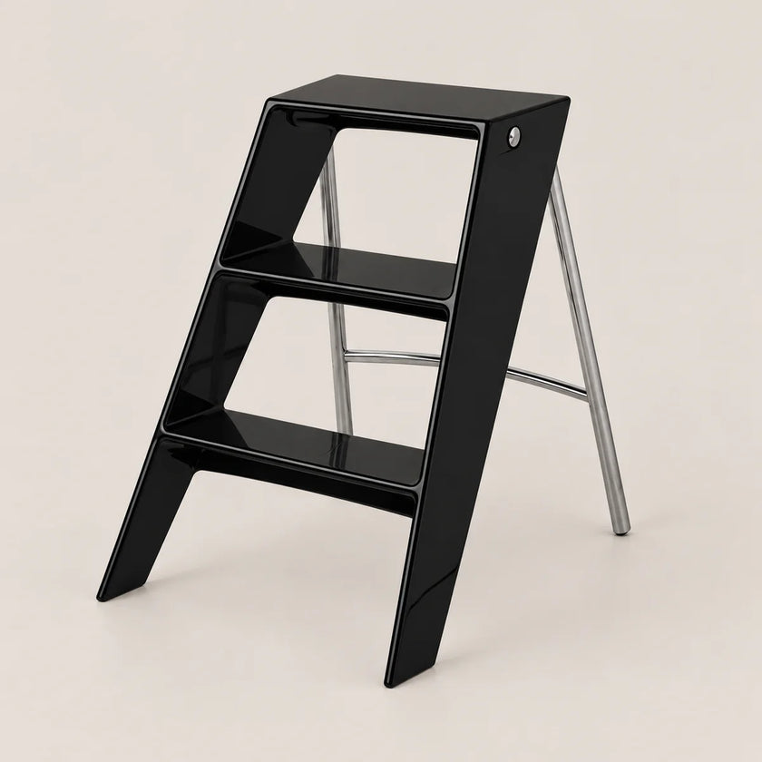 A modern black step stool with a glossy finish and silver metal support legs, shown on a clean, solid light beige background.