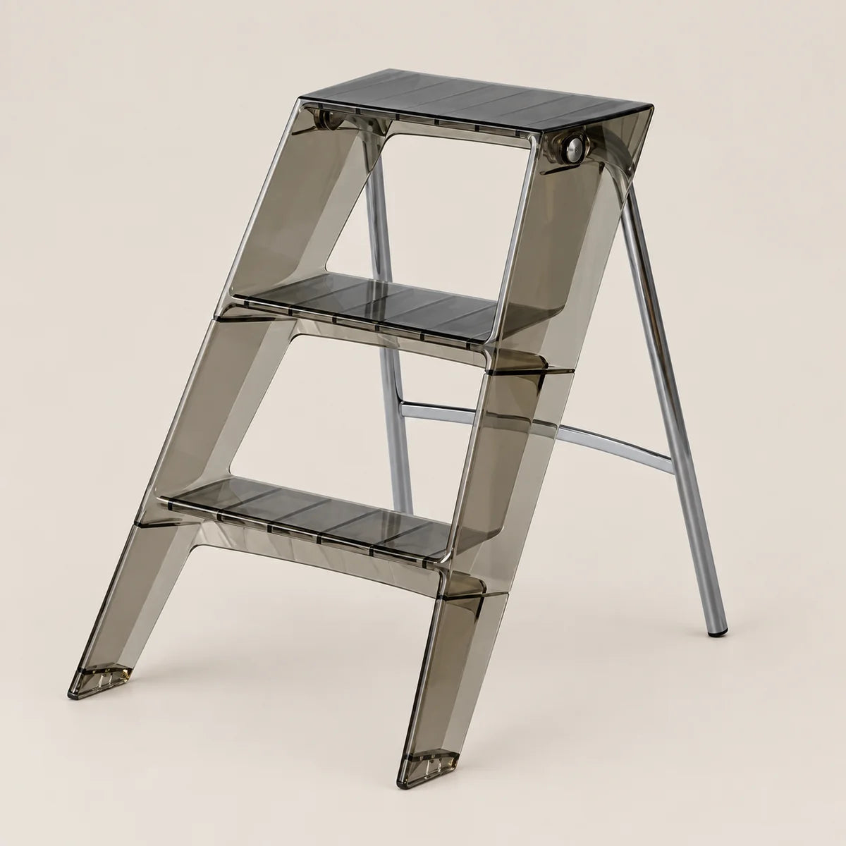 A three-step folding step ladder made of translucent smoky gray acrylic with black textured non-slip steps, shown on a solid light beige background.
