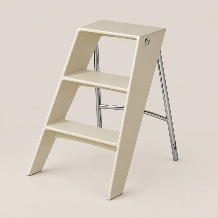 A minimalist two-step ladder stool in a warm cream color with a polished silver metal frame, shown on a solid light beige background.
