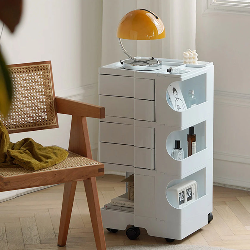 White storage cart with shelves and drawers next to a wooden chair in a room.