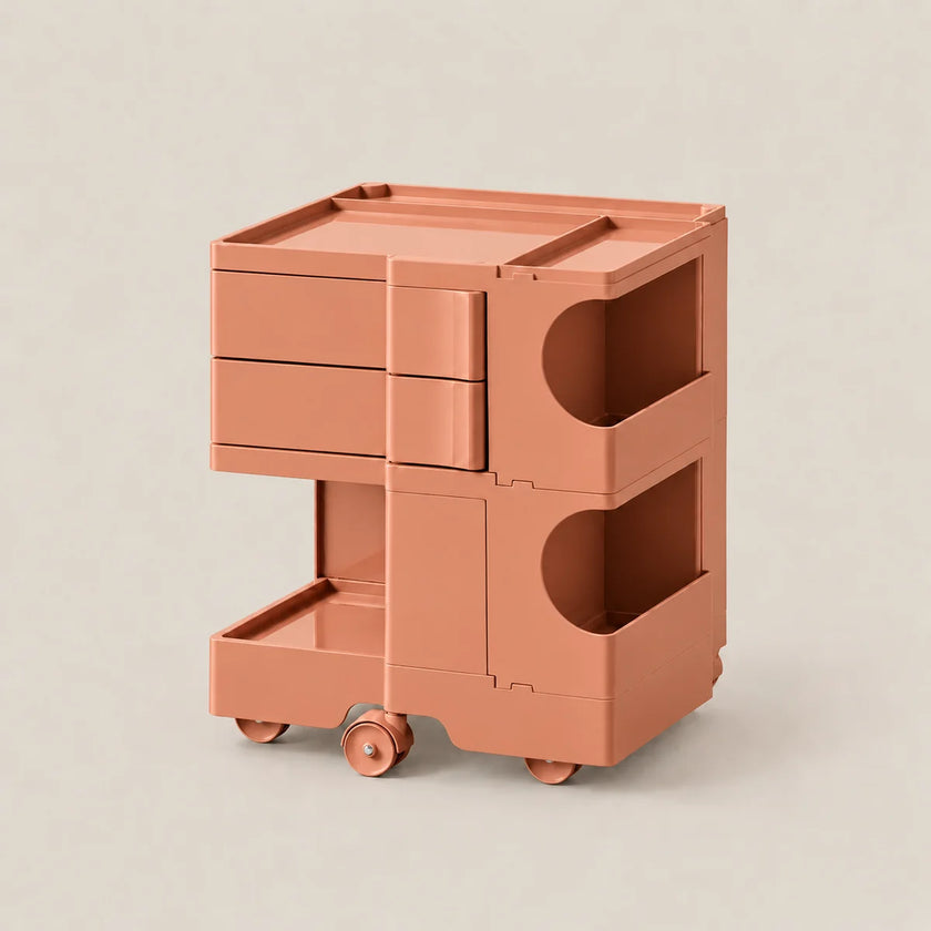 A modern two-tier rolling storage cart in a matte terracotta color, featuring three drawers on the top level, open side compartments, and a bottom pull-out tray on wheels, set against a solid light beige background.
