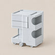 A light gray plastic rolling organizer cart with three drawers, two open side compartments, and a pull-out bottom tray, shown on a plain beige background.