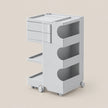 A light gray plastic rolling storage cart with three drawers on the left, two open shelves with curved cutouts on the right, and caster wheels at the base, shown on a plain beige background.
