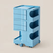 A light blue modular storage cart with multiple drawers, open side compartments, and caster wheels, shown on a plain beige background.