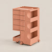 A three-tier rolling storage cart in a matte dusty rose or terracotta pink color, featuring four drawers on the left, two open shelves with curved cutouts on the right, and a lower pull-out tray on wheels, set against a solid light beige background.