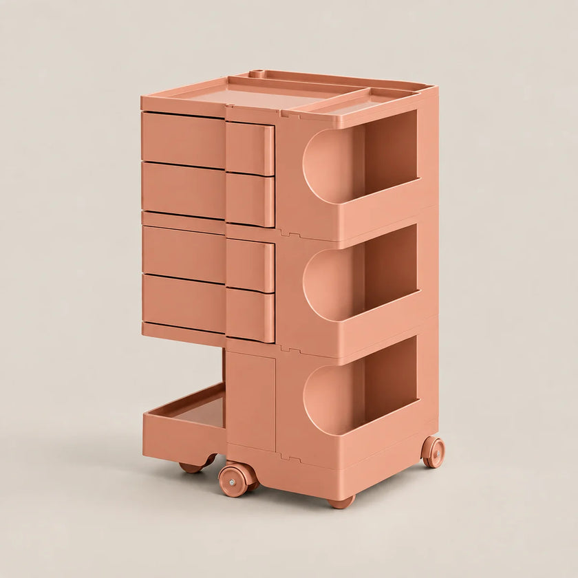 A three-tier rolling storage cart in a matte dusty rose or terracotta pink color, featuring four drawers on the left, two open shelves with curved cutouts on the right, and a lower pull-out tray on wheels, set against a solid light beige background.