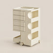 A cream-colored plastic rolling storage cart with five drawers on the left, three open storage compartments with curved cutouts on the right, and a pull-out tray at the bottom, shown on a solid light beige background.