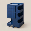 A dark blue rolling storage cart with multiple drawers, open shelves, and wheels, shown on a plain beige background.