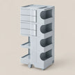 A light gray rolling storage cart with multiple drawers and open shelves, shown on a plain beige studio background.