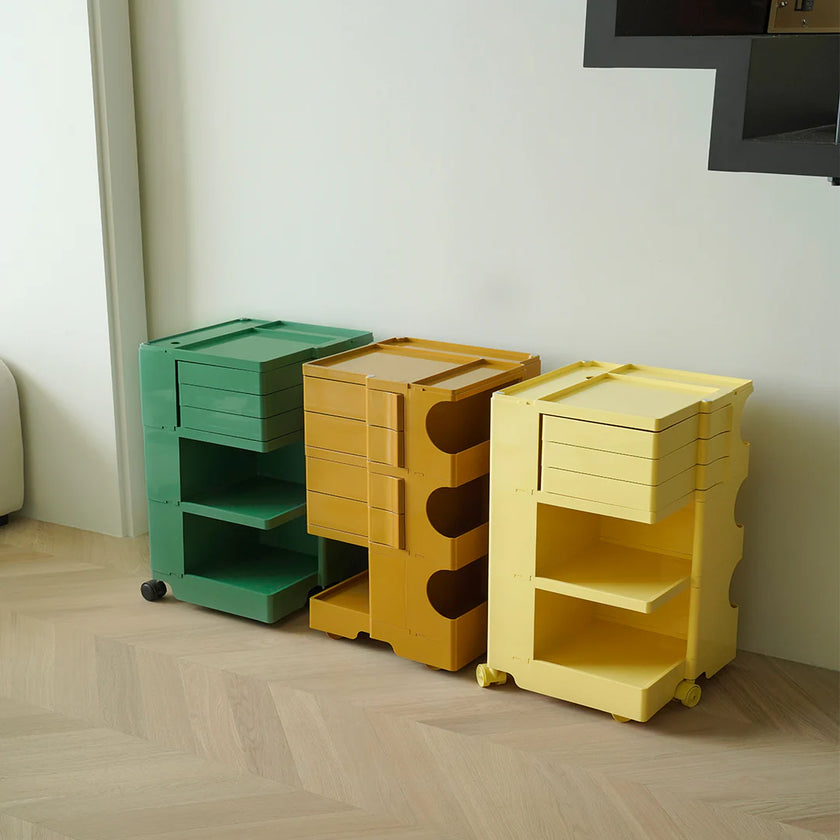 Three colorful storage units in green, yellow, and beige on a wooden floor.