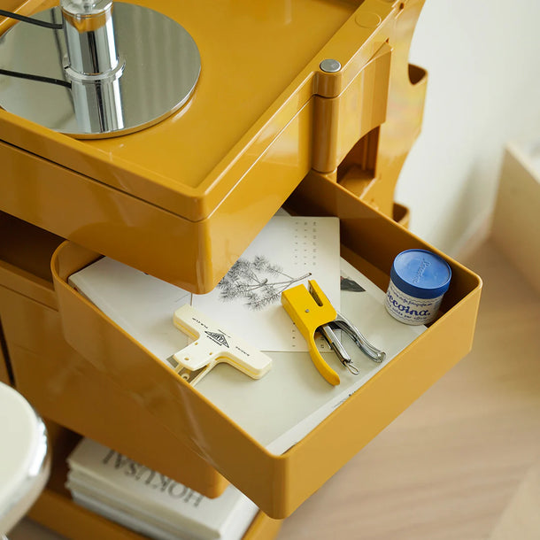 Yellow desk with open drawer containing stationery items on a wooden surface.