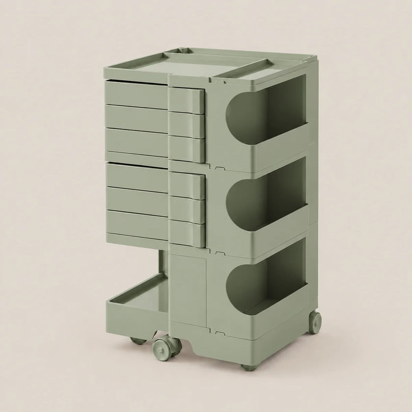 A sage green rolling storage cart with multiple drawers and open shelves, shown on a plain warm beige studio background.